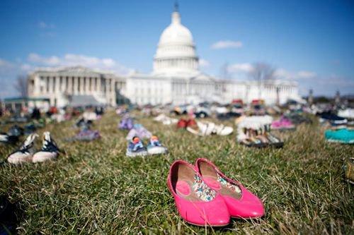 资料图：2018年3月，民众将多年里枪击事件中遇难儿童的鞋子摆放在华盛顿国会山前的草坪上，抗议国会面对枪击频发现状的不作为。（图片来源：新华社）