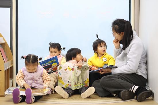 2月2日，南京晨星托育江心洲园里，老师与孩子们一起阅览书籍。