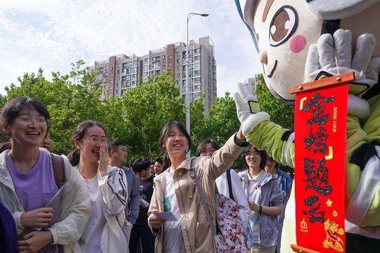 6月7日，在江苏省南京市建邺区中华中学考点，考生与送考人偶击掌。新华社记者 李博 摄