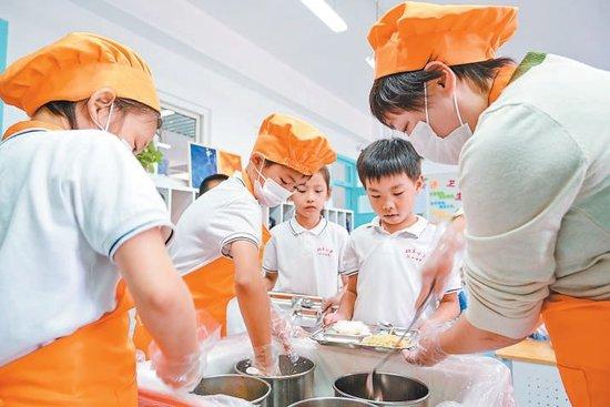 北京小学红山分校二年级教室内，班主任老师和两名“膳食小卫士”现场为同学们打饭。实习记者金瑶摄