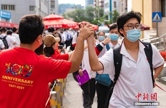 6月7日上午，北京市朝阳区陈经纶中学考点外，参加高考的学生入场前与送考老师击掌。当日，2022年全国高考拉开帷幕。 中新社记者 侯宇 摄