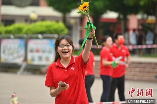 一名老师手持葵花为高考学子送祝福，盼学子一举夺魁。俞靖摄