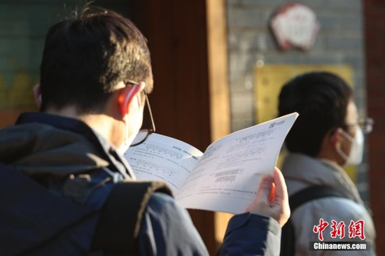 资料图：1月8日，江西南昌市第二十八中学考点外，一名考生拿着资料在复习。中新社记者 刘力鑫 摄