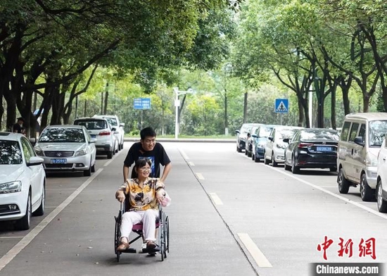 赵建军用轮椅推着母亲在校园散心。受访者供图