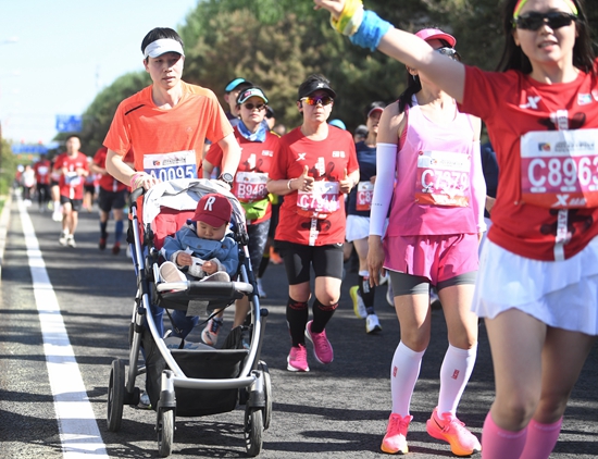  4月16日，一位家长跑者推着孩子参加北京半程马拉松。视觉中国供图